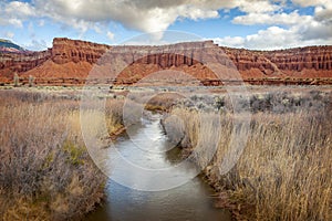 Fremont River Flowing Under Red Sandstone Cliff. photo